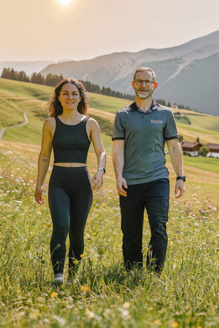 Zwei TrainerInnen durchstreifen eine Wiese im Allgäu
